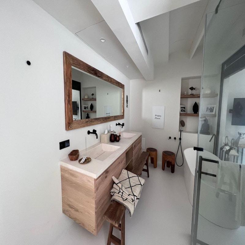 Baño minimalista con tocador de madera y ducha de vidrio en Ibiza.