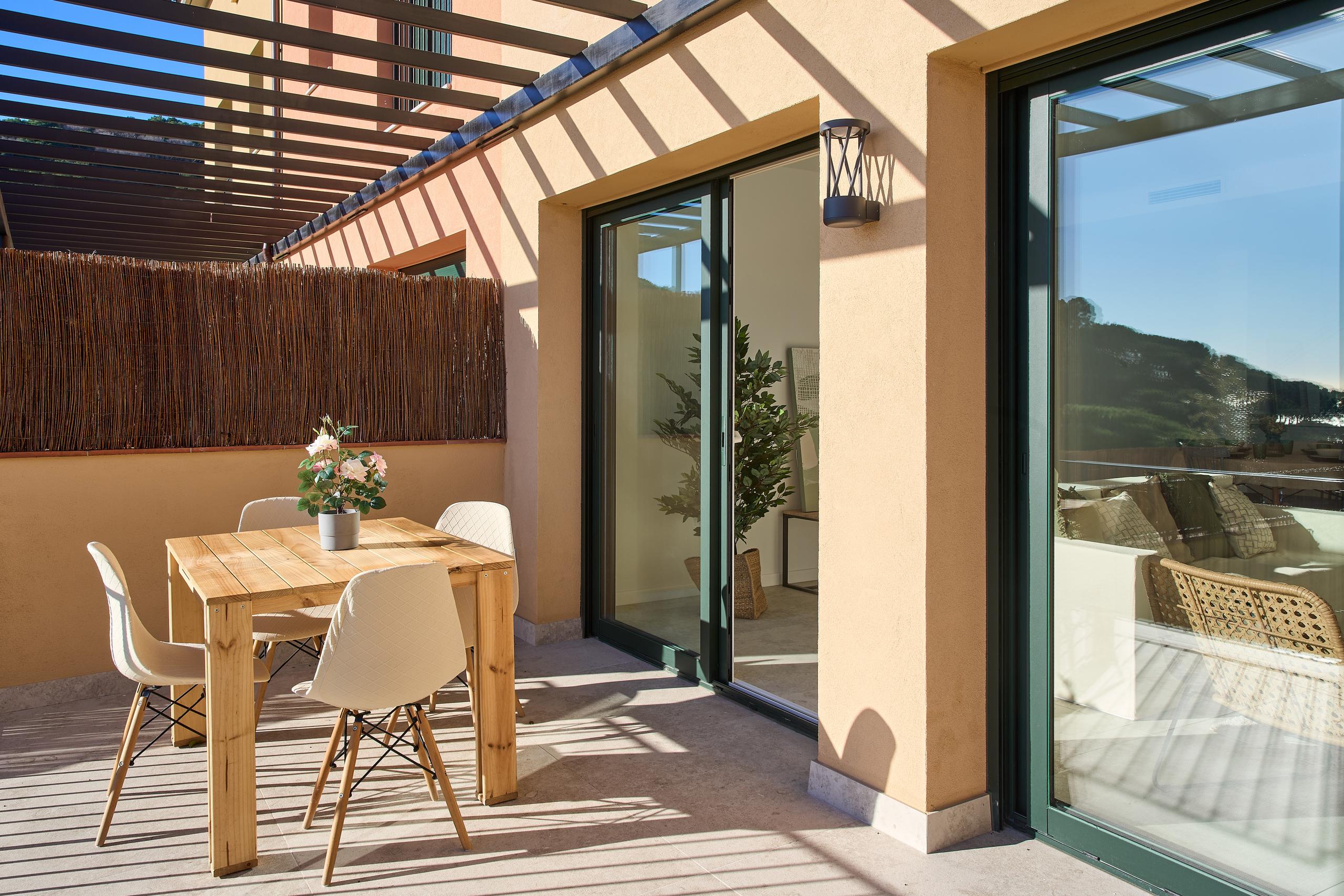 Terraza privada con mesa de comedor exterior de madera y sillas modernas, ideal para disfrutar