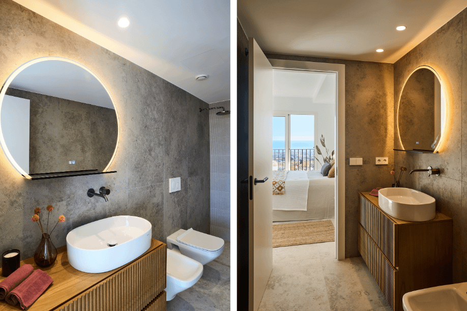 Baño moderno con lavabo ovalado, espejo circular retroiluminado y paredes de piedra gris